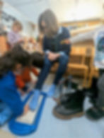 Adult helps children measure shoe sizes with foot measuring device.