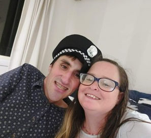 A smiling Becky and Mitch pose for a casual indoor selfie while sitting together on the couch.