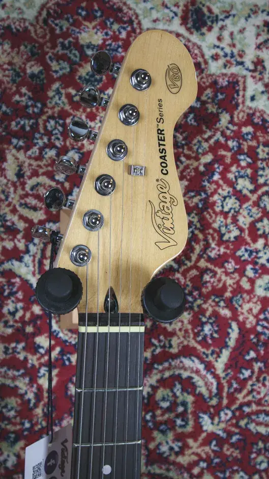 Thumbnail: Close-up of the Vintage V60 Coaster Series headstock front, featuring the Vintage logo and tuning pegs.