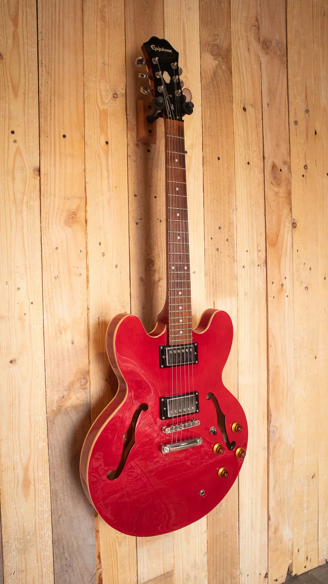 Full-length view of the Epiphone Dot on a wooden background, displaying its semi-hollow body and Cherry Red color.