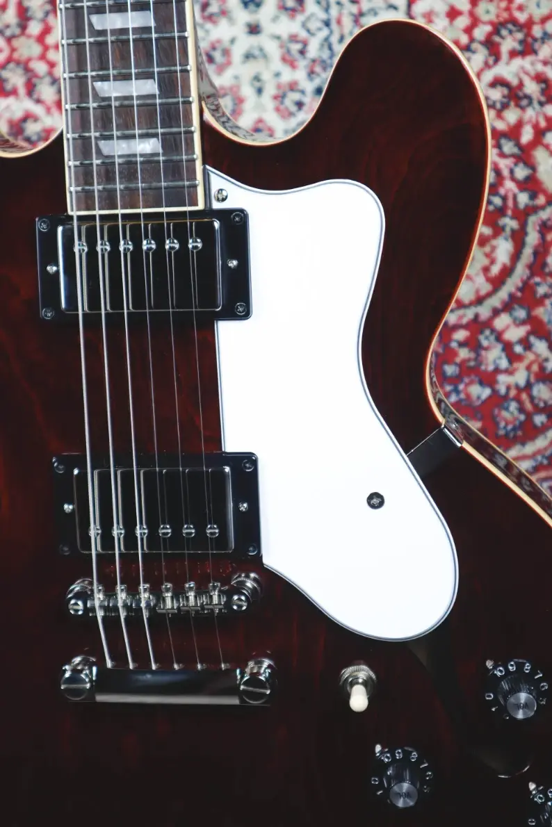 Thumbnail: Epiphone Noel Gallagher Riviera semi-hollow electric guitar in Wine Red finish with dual humbuckers and white pickguard.