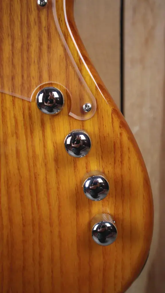 Thumbnail: Close-up of the control dials and switch on the Cort GB74 JJ Amber Bass.