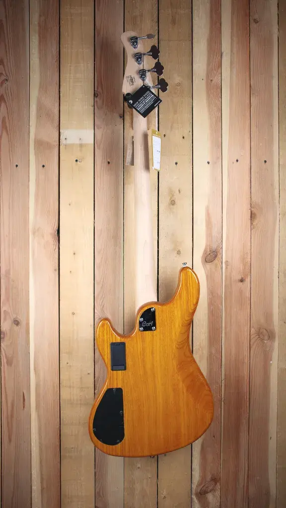 Back view of the Cort GB74 JJ Amber Bass, hanging on a timber wall.