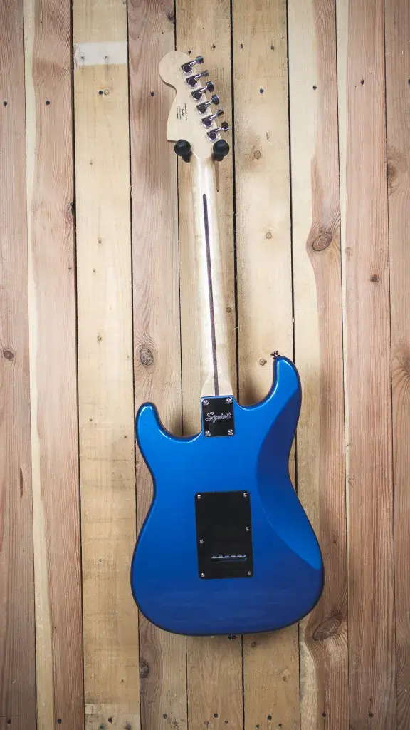 Back view of the Squier Affinity Stratocaster on a timber wall hanger, highlighting the pristine Lake Placid Blue finish.