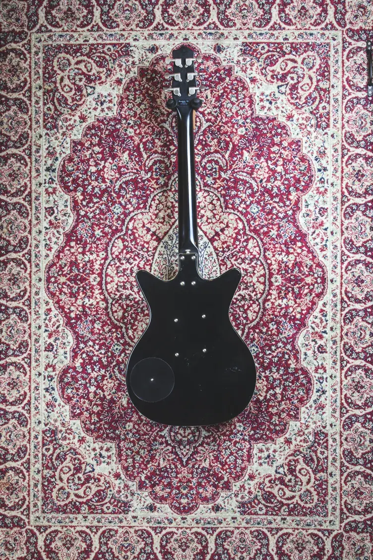 Danelectro DC59 Matte Black – Rear view showing full body and neck on patterned rug.