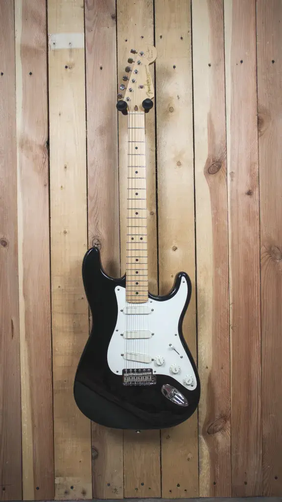 Front view of a 1994 Eric Clapton 'Blackie' Stratocaster in black, displayed on a timber wall hanger.