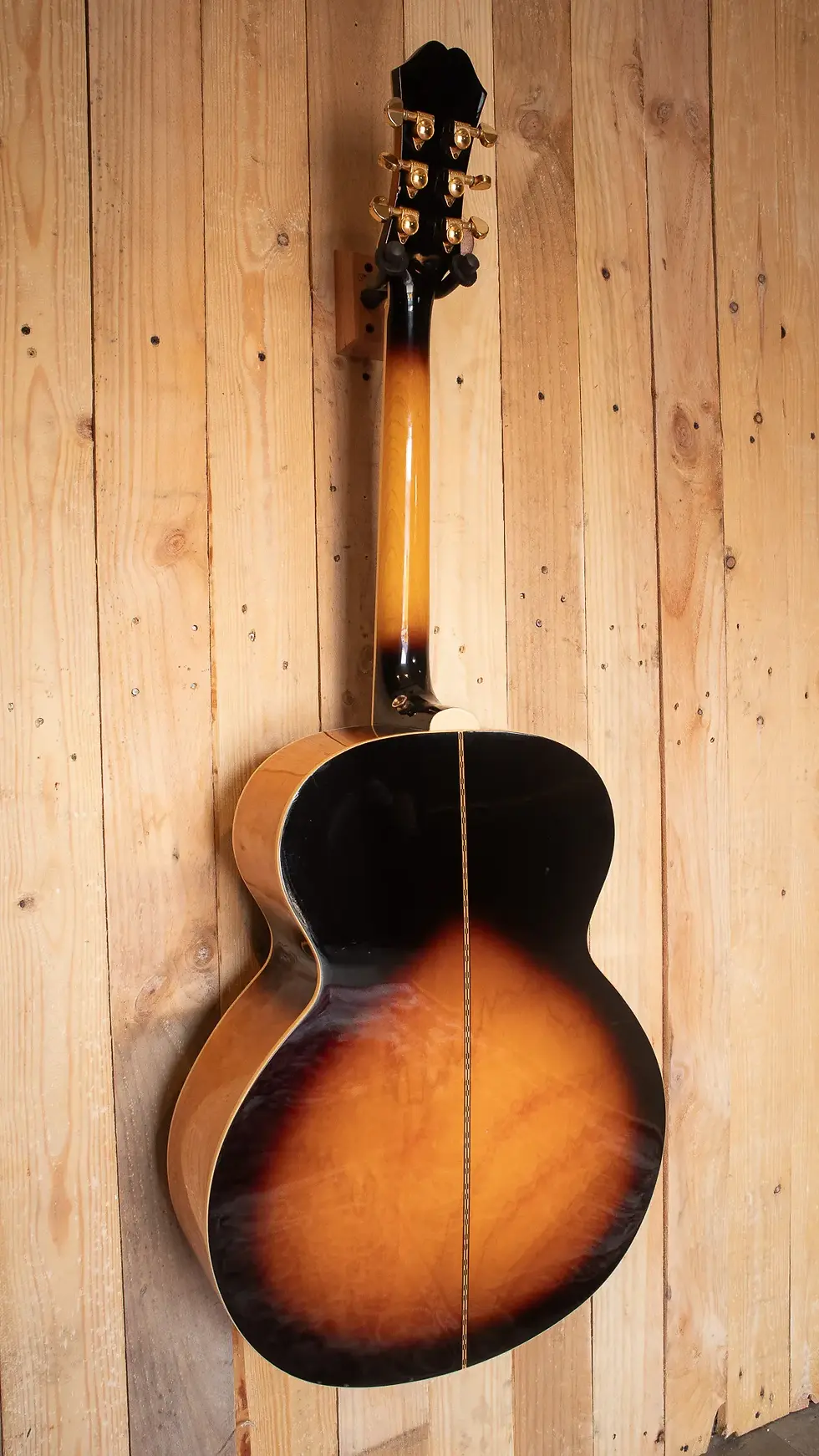 Backside view of Epiphone EJ-200 VS full body against a rustic backdrop
