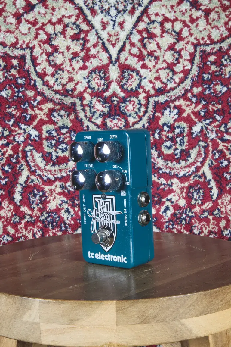 TC Electronic John Petrucci Dreamscape pedal on a wooden stool with patterned rug backdrop, angled slightly to the left.