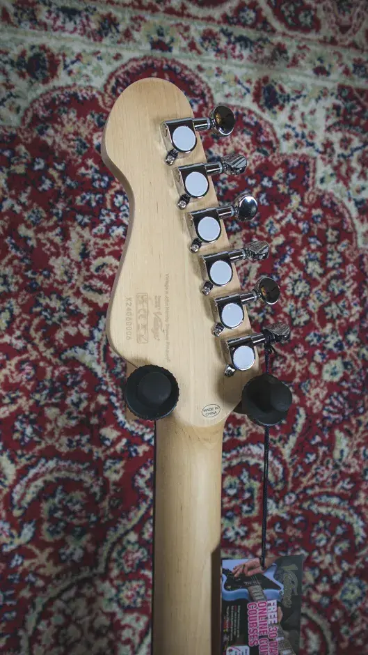 Thumbnail: Close-up of the back of the Vintage V60 Coaster Series headstock, showing tuners and serial number detail.