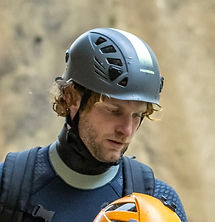 Portrait of the expert canyoning instructor (called Yoann Bervas) equipped with a bag, a helmet and his neoprene suit in the middle of a canyon