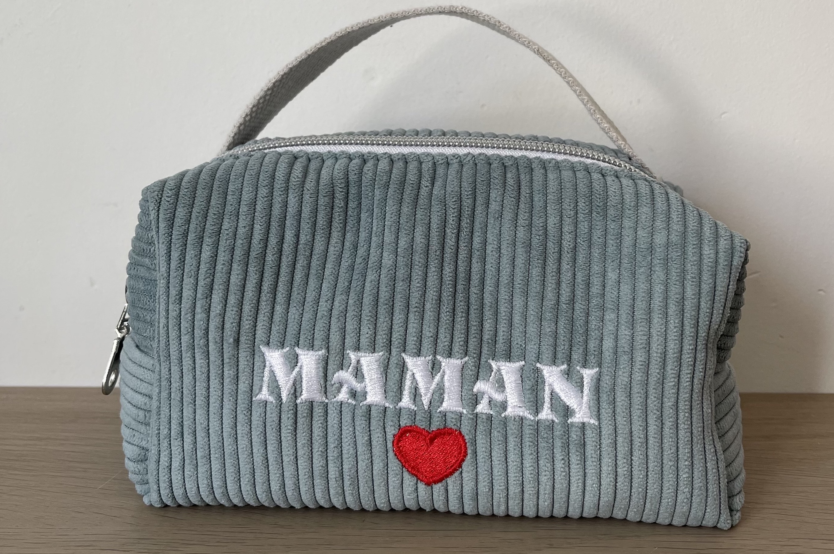 Sac à main bleu-gris en velours côtelé avec poignées; motif « MAMAN » en blanc et cœur rouge au centre.