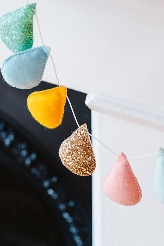Close up image of some colourful fabric padded bunting draped in front of a white fireplace
