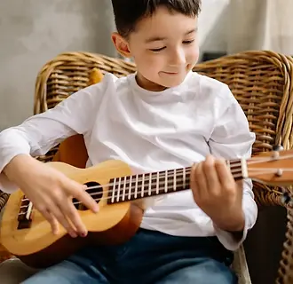 A young boy playing the ukulele