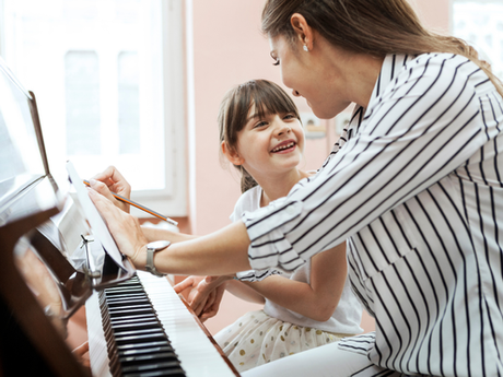 A young girl listen attentively to her piano teacher during her piano lesson