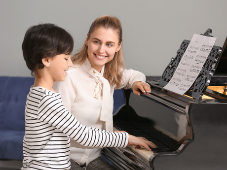 Piano teacher smiling with a young student during a lesson