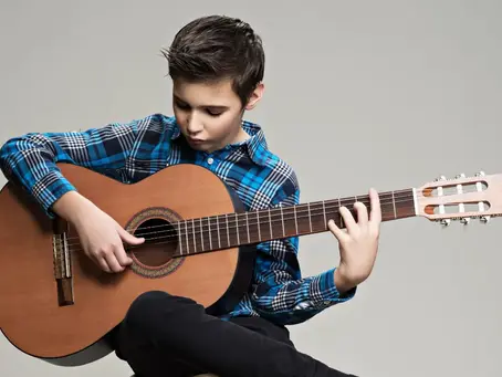 A teenage boy playing an acoustic guitar