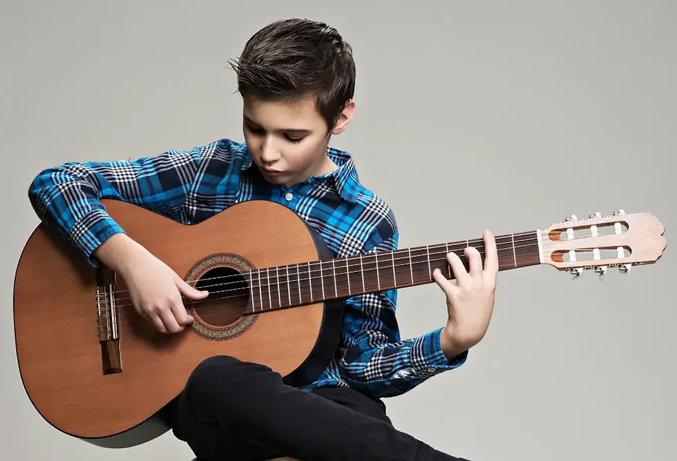 A teenage boy playing an acoustic guitar.