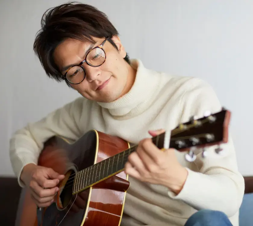 An adult practicing on an acoustic guitar.