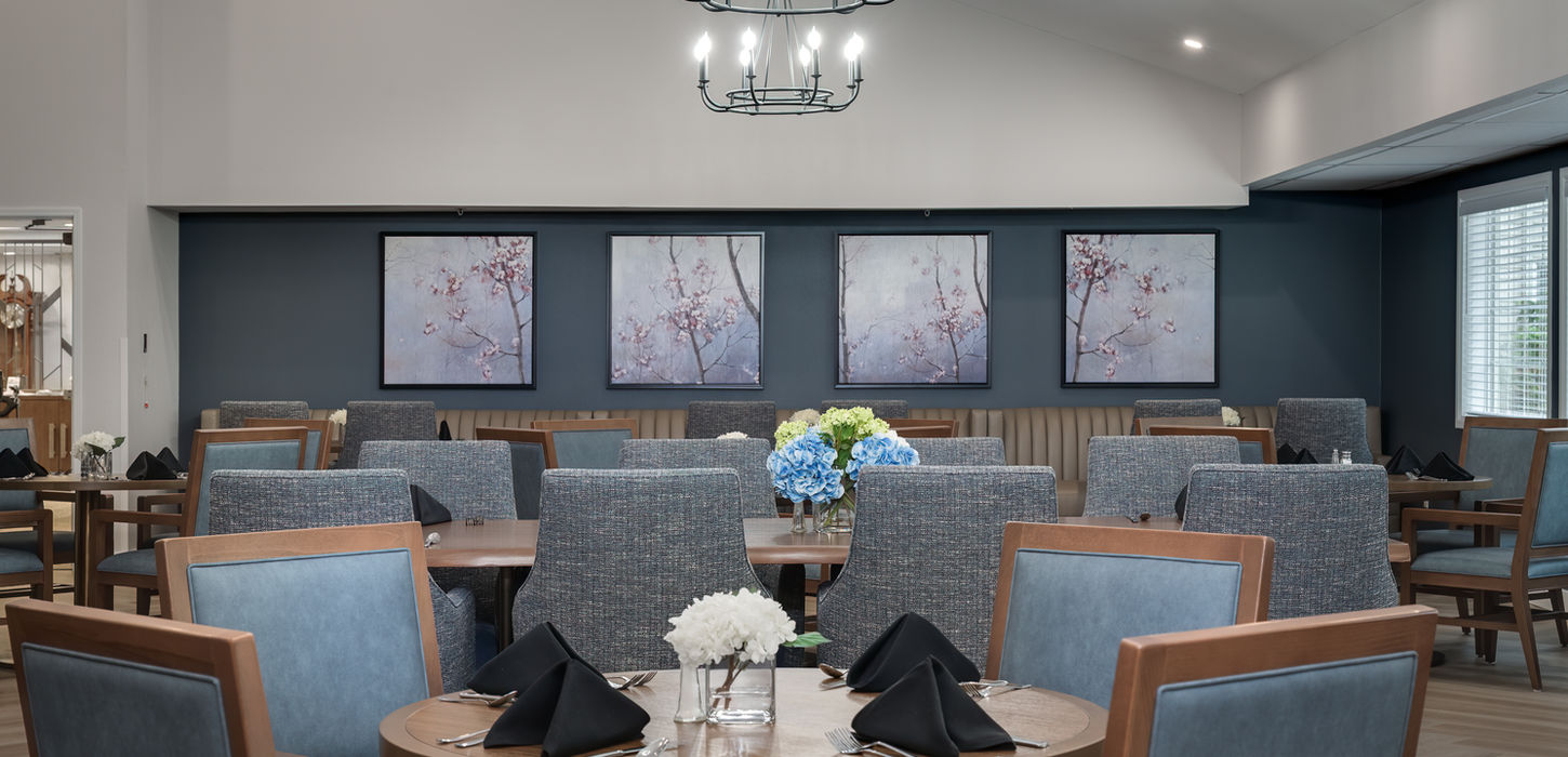 Elegant dining room with tables, chairs, art, and a chandelier in focus.