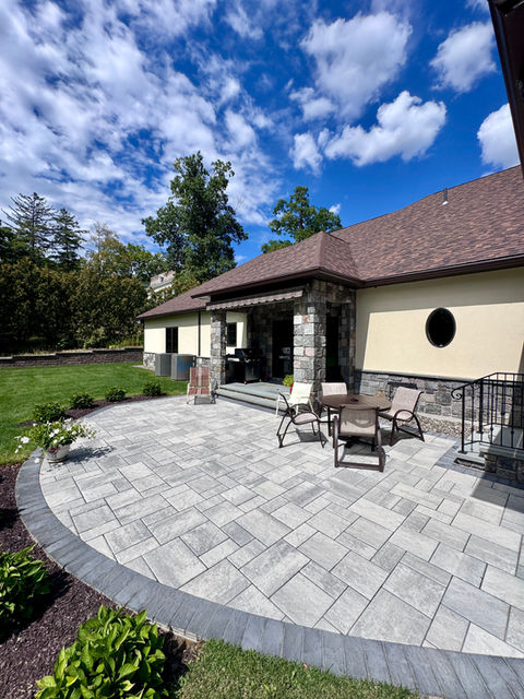 Techo-Bloc paver patio with curved border and covered outdoor seating area beside a home in Niskayuna, New York