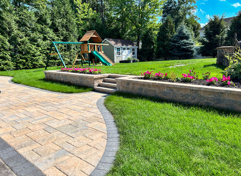 Long Versa Lok retaining wall with landscaped planting bed and green lawn in Niskayuna, New York