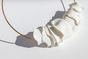 a close up of a necklace with white petals on a white surface