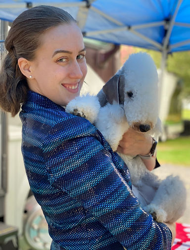 Katie in a sparkly blue striped jacket holding a Bedlington Terrier