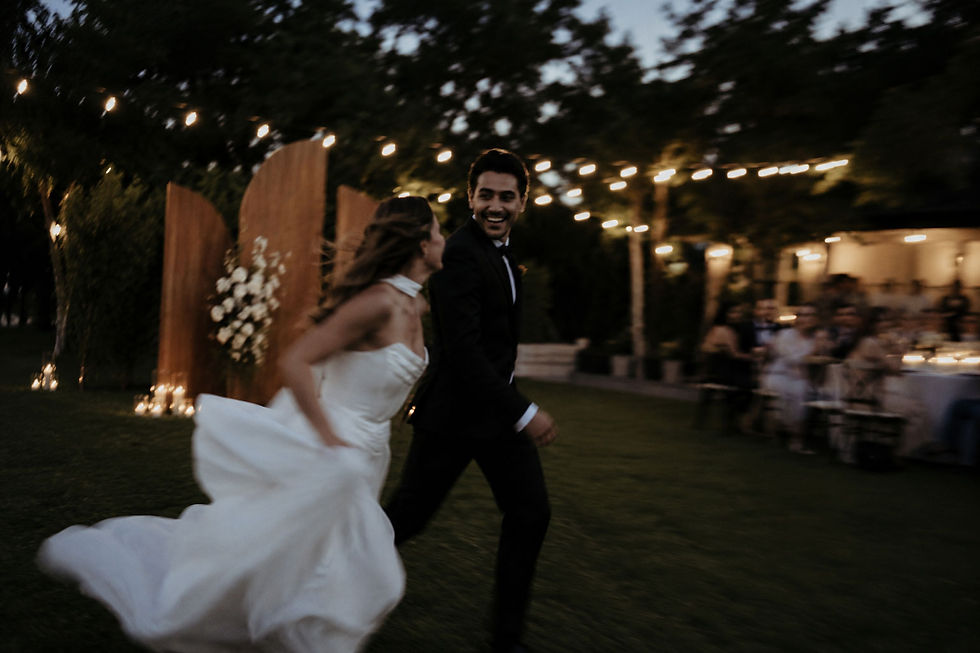Custom wooden wedding backdrop with white floral accents at an elegant outdoor evening reception