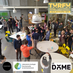 Groupe de personnes dans une salle d’atelier. Souriantes, elles sont tournées dans différentes directions, certaines en petits groupes. La plupart lèvent un bras.