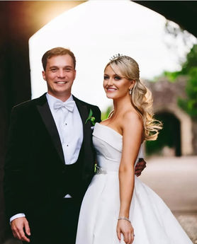 Happy wedding couple poses for photo. Bride has her hair styled in a half up style.