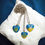 Thumbnail: Heart-shaped Ukrainian pendant necklaces with Tryzub and peace dove designs on blue and yellow backgrounds.