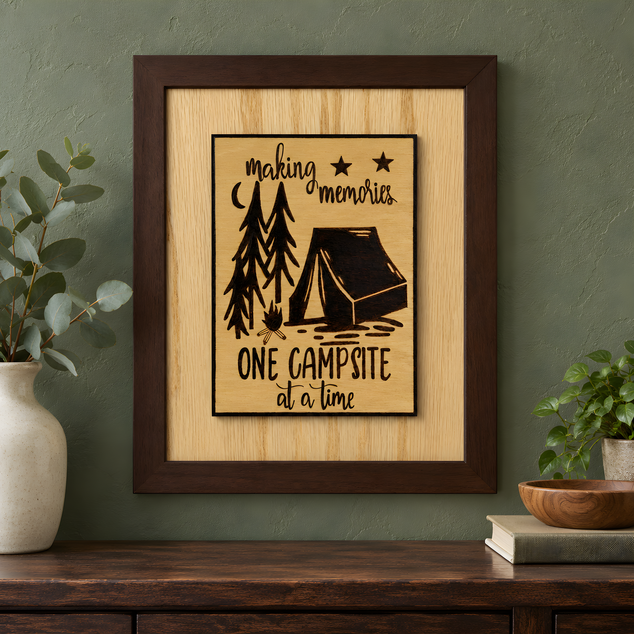 Handmade camping wood sign gift in a brown frame hanging on a sage green wall above a wooden console.