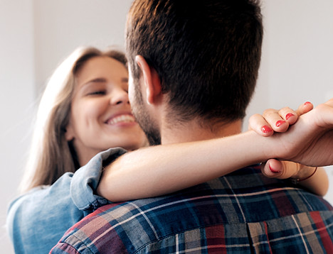 Hugging couple smiling in new home with
