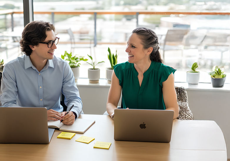 Two people collaborating at a desk, representing guided support and clarity through conversation.