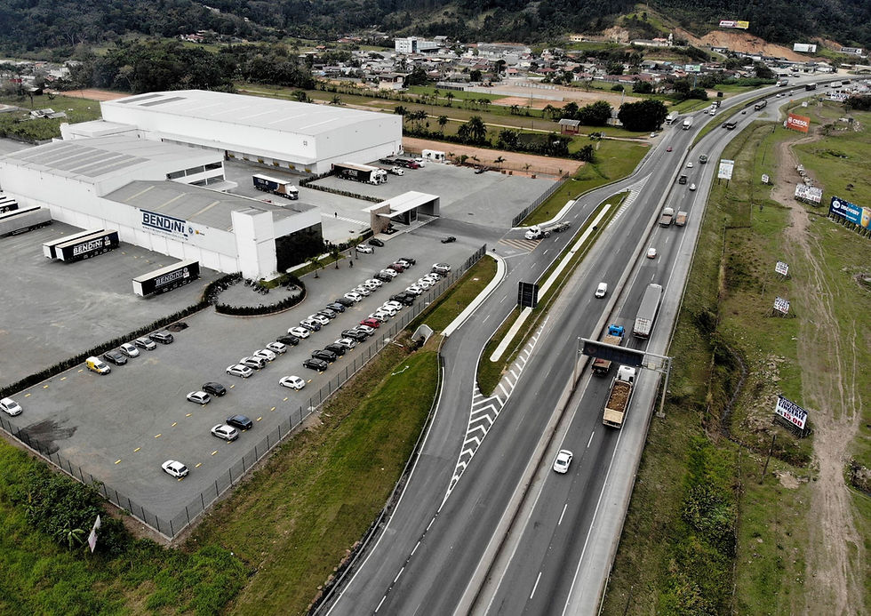 TEXTO ALTERNATIVO: Imagem aérea de rodovia com acesso regularizado a um empreendimento logístico, mostrando faixas de aceleração e desaceleração, sinalização viária e integração segura entre a via principal e o acesso ao empreendimento.