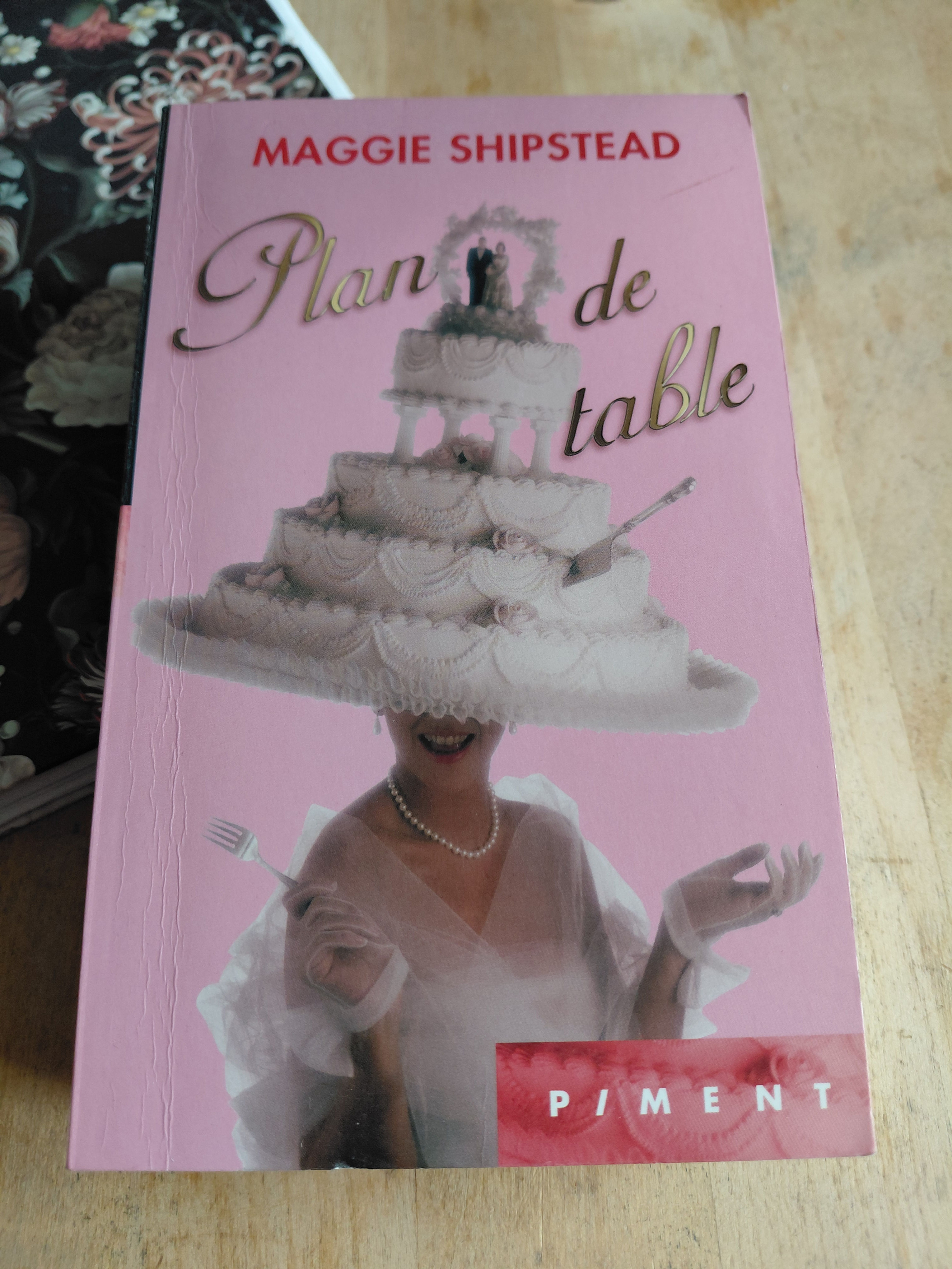 Couverture rose du livre Plan de table par Maggie Shipstead, collection Piment, illustrée d'un grand gâteau de mariage.