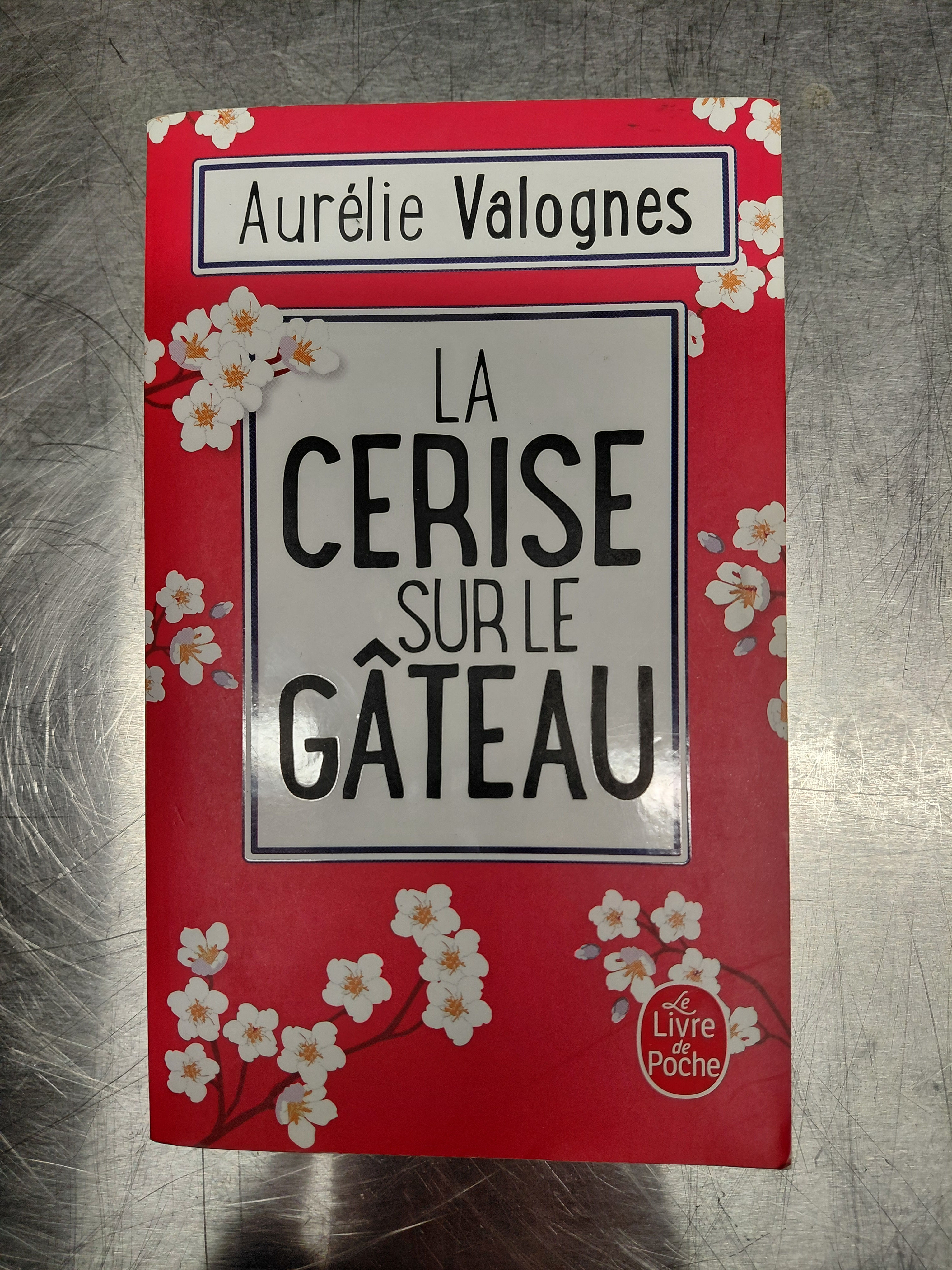 Couverture rouge du roman La cerise sur le gâteau d'Aurélie Valognes décorée de fleurs blanches.