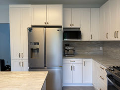 A bright and modern kitchen featuring white shaker cabinets, a spacious waterfall island, and sleek stainless steel appliances.