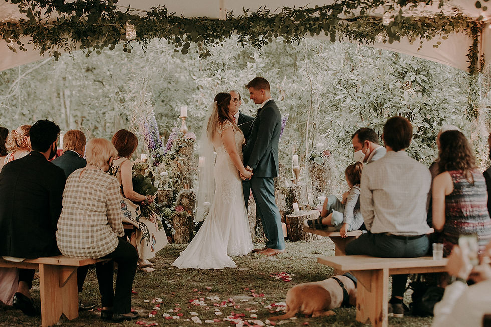 Bride and Groom during their wedding ceremony in a tent surrounded by greenery.