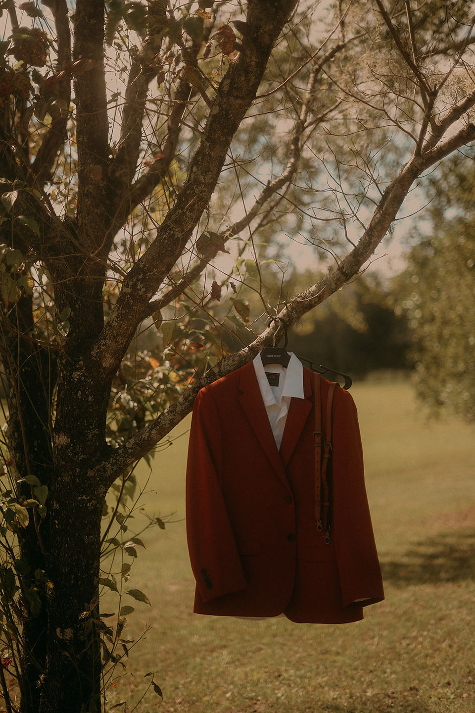 A rust colored blazer hanging on a tree limb