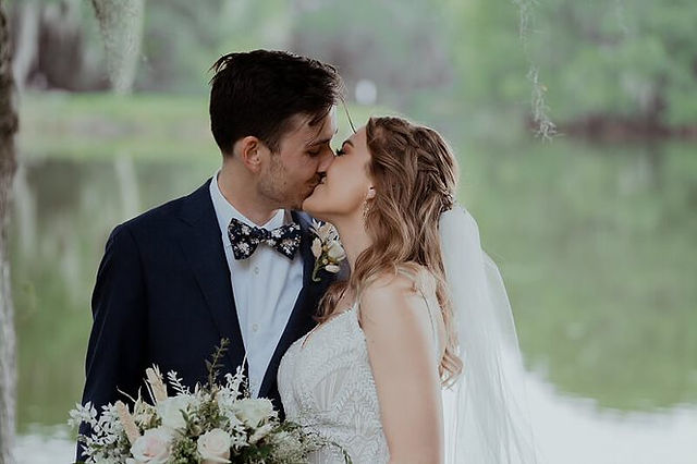 A bride and groom kissing with a lake in the background