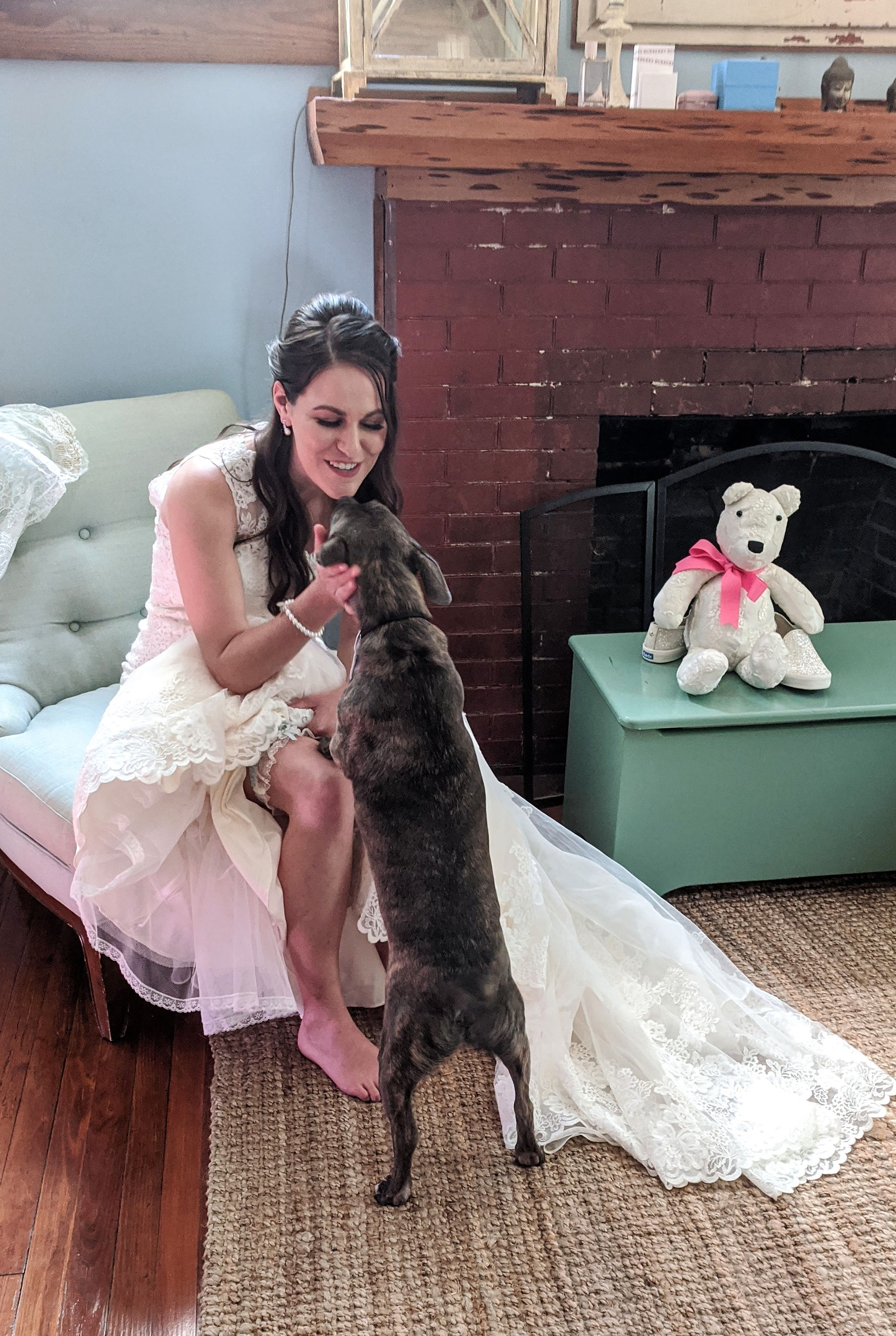 A bride sitting down while her dog tries to climb into her lap