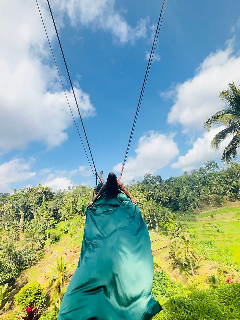 Dr. Tea in a green flying dress in a swing over rice terraces in Bali