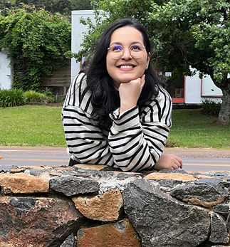 Imagem de mulher com mão no queixo e olhos voltados para cima numa paisagem verde