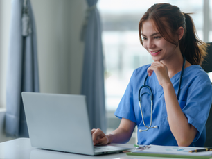 A happy healthcare worker looking at a laptop.
