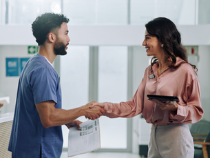 A healthcare admin shaking hands with a new hire at a healthcare facility.