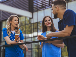 Three healthcare workers outside having a conversation, all wearing different colored scrubs
