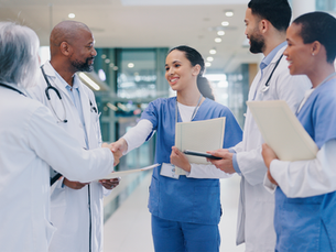 A group of doctors and nurses shaking hands with a new employee.