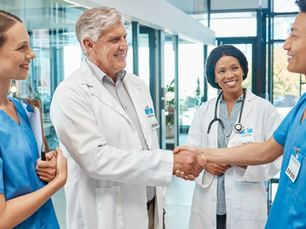 A healthcare team meeting a new employee and one person shaking the new employee's hand.