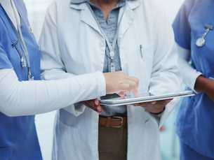Healthcare employees looking and pointing at a tablet.